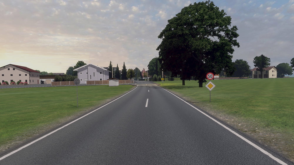 Screenshot from the mobile game Drive Real Truck Simulator: Road leading through a countryside setting with green fields, scattered houses, and a large tree under a partly cloudy sky.