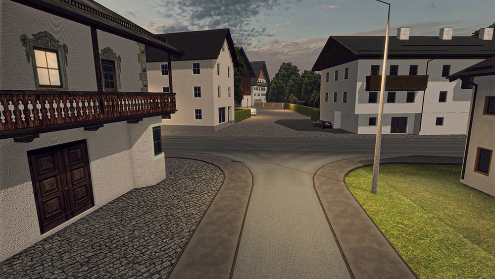 A serene intersection in a small European-style town, featuring traditional white buildings with wooden balconies and decorative elements. The road is paved with cobblestones, and a streetlight stands on the right. In the background, you can see more houses and greenery under a partly cloudy sky.